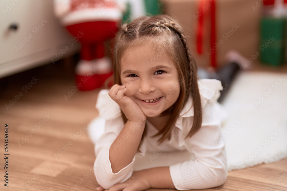 Adorable hispanic girl smiling confident lying on floor by christmas tree at home Adorable hispanic girl smiling confident lying on floor by christmas tree at home