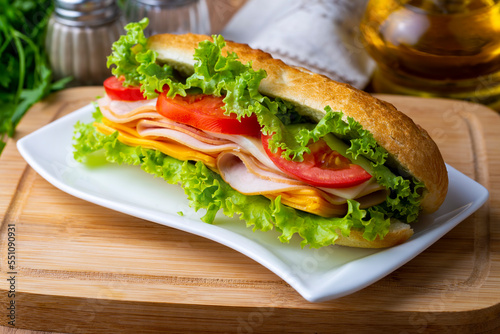 Cheese, ham, lettuce and tomato slices in an appetizing tasty sandwich.