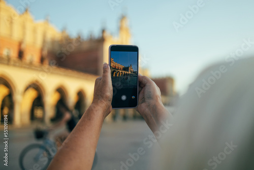 A hand taking photo of Sukiennice with smartphone, Krakow, Poland