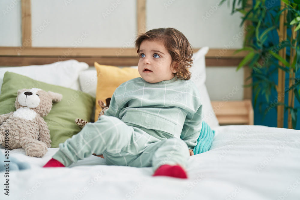 Adorable hispanic girl sitting on bed with relaxed expression at bedroom Adorable hispanic girl sitting on bed with relaxed expression at bedroom