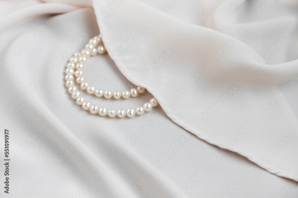 Fototapeta premium Pearls necklace on creme off-white silky background