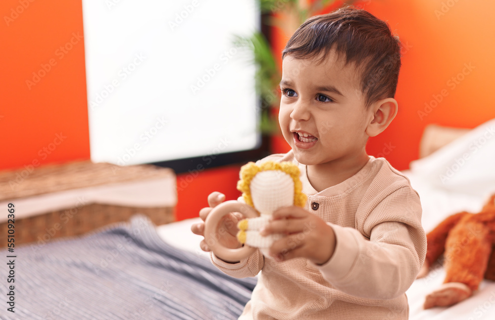 Adorable hispanic toddler playing with dolls sitting on bed at bedroom Adorable hispanic toddler playing with dolls sitting on bed at bedroom