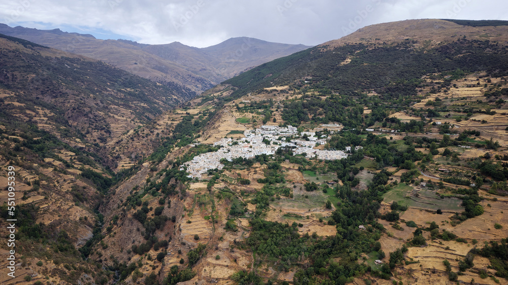 Aerial drone view of the village Capileira with Sierra Nevada Mountain in the background. Rural tourism and beautiful mountain destinations. La Alpujarra region in Spain.