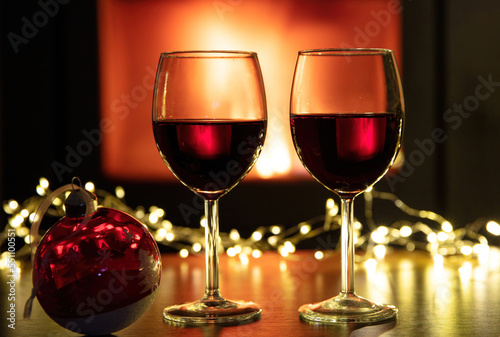 Christmas celebration. Red wine glasses and decoration on table  fireplace background. Xmas celebration