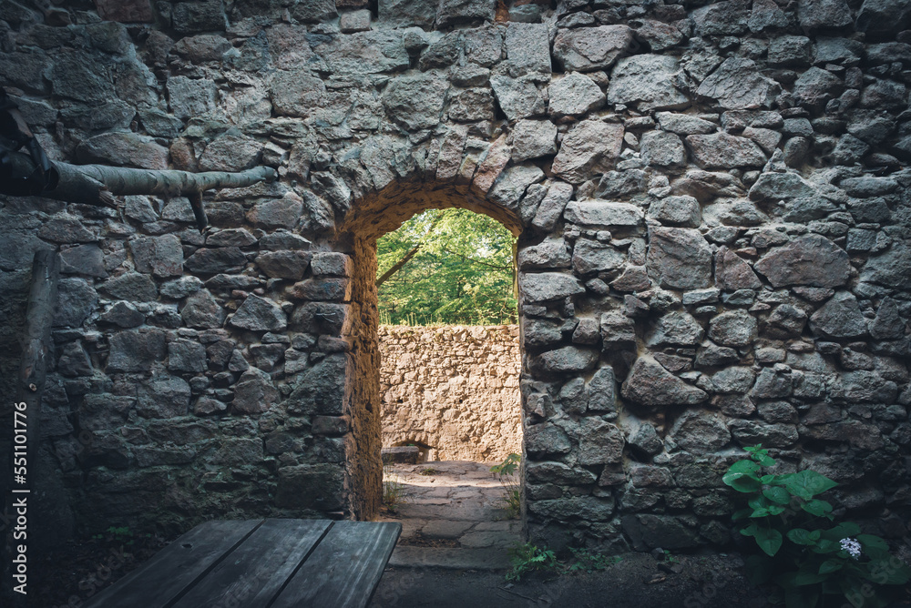 Fototapeta premium A doorway in the wall of a ruined castle through which sunlight spills.