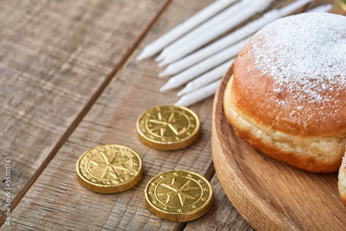 Happy Hanukkah. Hanukkah sweet doughnuts, gift boxes, white candles and chocolate coins on old  wooden background. Image and concept of jewish holiday Hanukkah. Top view. photo