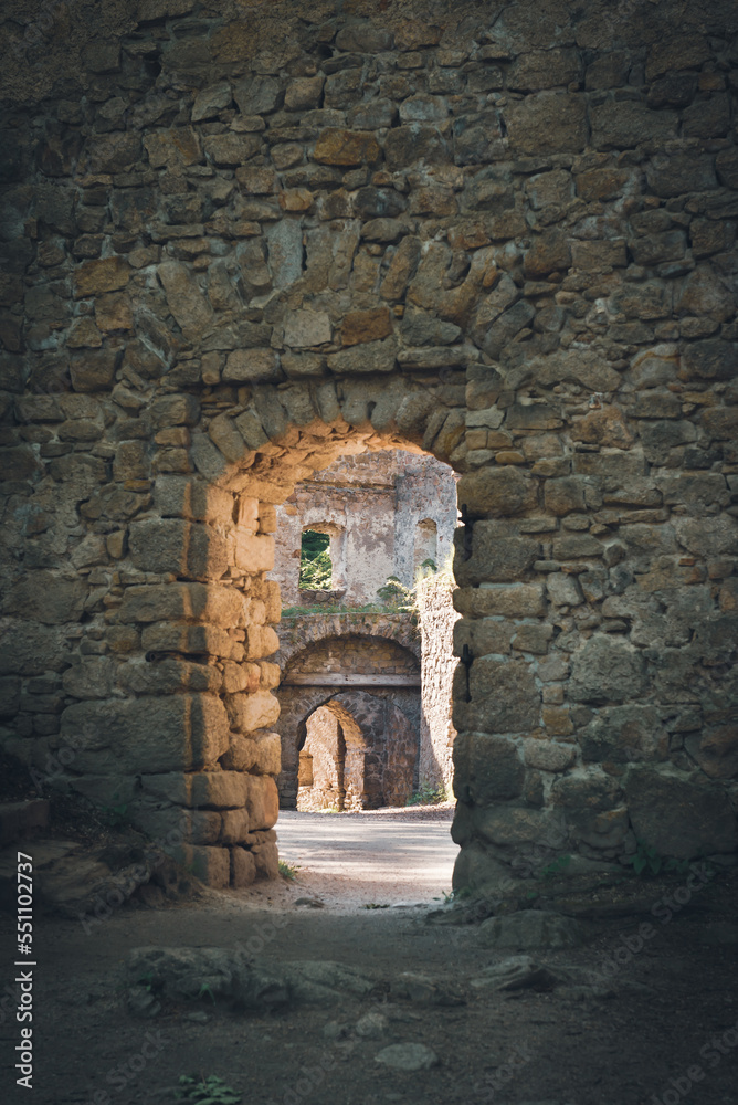Obraz premium A doorway in the wall of a ruined castle through which sunlight spills.