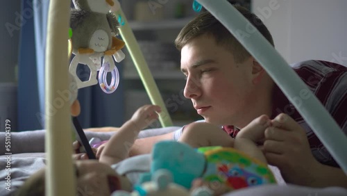 A young father lies on the bed with a phone