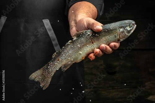 Fototapeta Naklejka Na Ścianę i Meble -  Male hands holding rainbow trout with spices, Fresh seafood. Healthy food, diet or cooking concept