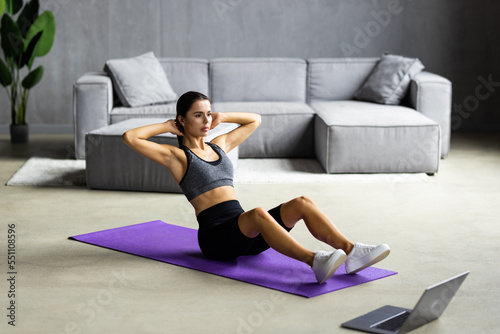 Slim sporty woman doing v-ups abs workout at home