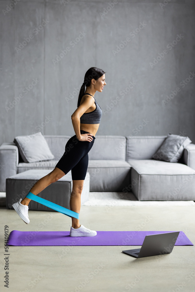 Young Woman during her fitness workout at home with rubber resistance band Young Woman during her fitness workout at home with rubber resistance band