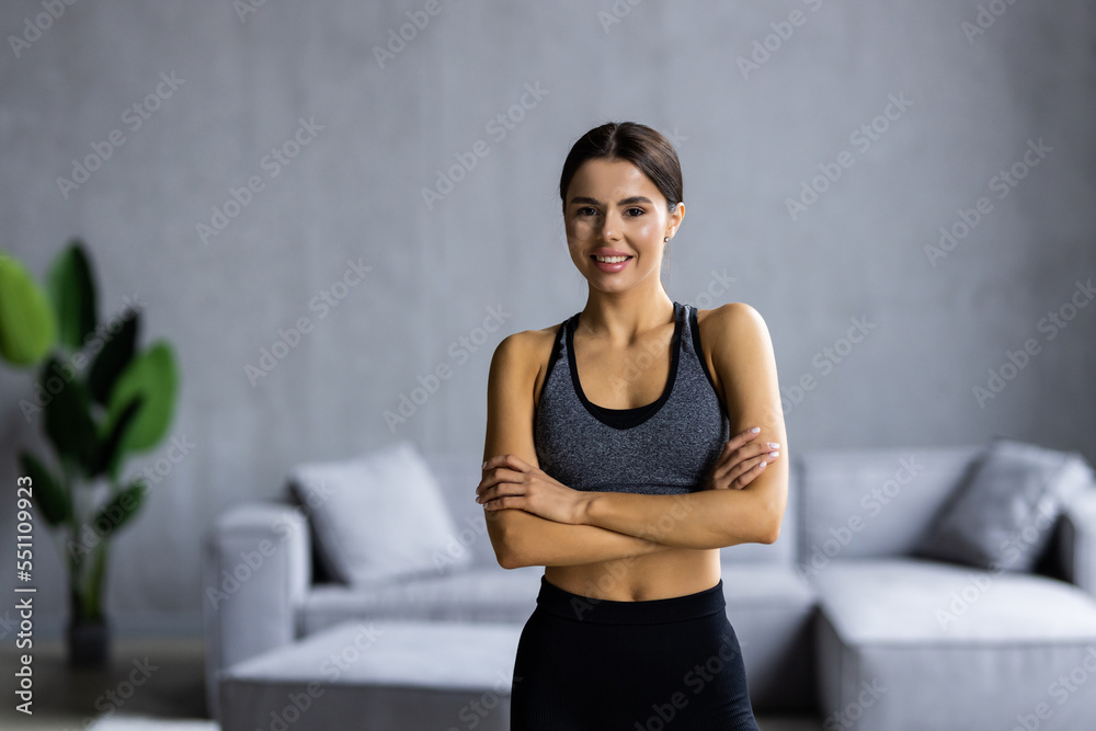 Fit young woman smiling at camera at home in bright room