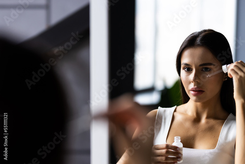 Billede på lærred Portrait of young woman applying hyaluronic acid at home
