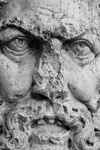 Carved face of man.  Closeup of mysterious male facial expression, scary looking, closeup of eyes, damaged nose and mouth. 