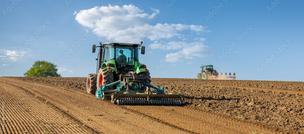 Obraz premium Agriculteur au volant de son tracteur au printemps dans les champs.