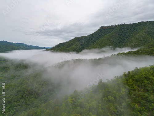 Aerial top view of forest trees with fog mist and green mountain hill at sunset. Nature landscape background, Thailand.