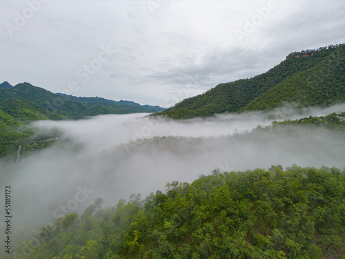 Aerial top view of forest trees with fog mist and green mountain hill at sunset. Nature landscape background, Thailand.