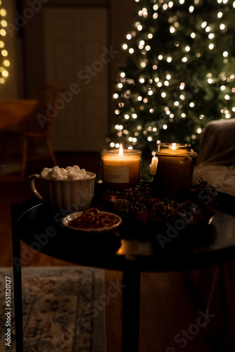 New Year 2022-2023. New Year's decoration. Christmas tree. Candle near the Christmas tree for the holiday. Marshmallow and hot chocolate in a cup.