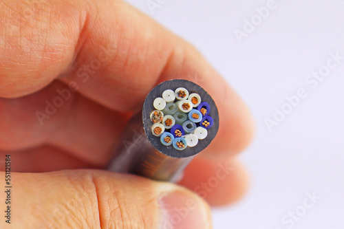 The hand holds stranded copper wires in colored insulation. On a white background.