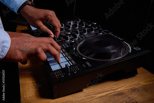 Popular musician, professional DJ at the console in the club. A stylish dark-skinned man at a music concert gives out modern music at the DJ console. Close up