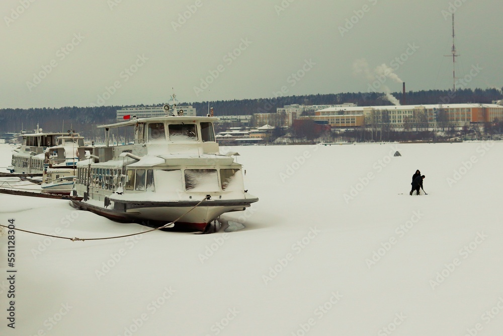 Winter, pleasure ships in the winter parking at the pier, on a frozen lake