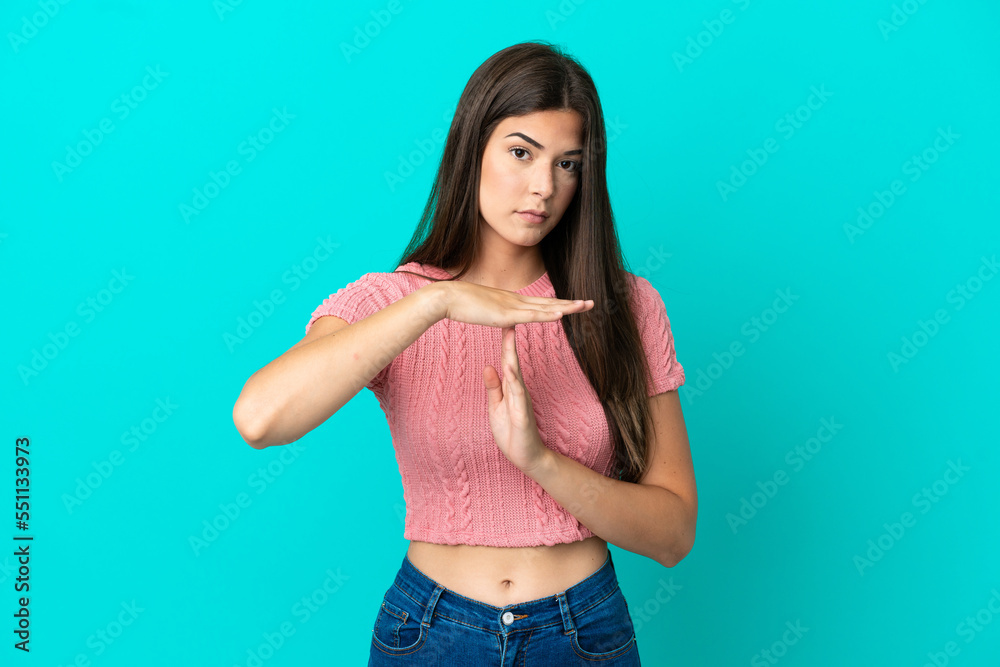 Young Brazilian woman isolated on blue background making time out gesture Young Brazilian woman isolated on blue background making time out gesture