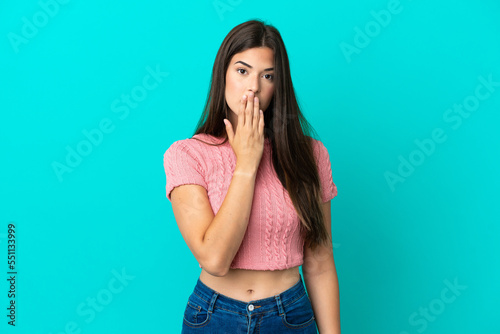 Young Brazilian woman isolated on blue background covering mouth with hand