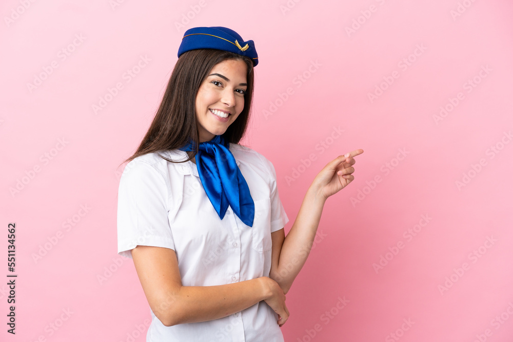 Airplane stewardess Brazilian woman isolated on pink background pointing finger to the side Airplane stewardess Brazilian woman isolated on pink background pointing finger to the side