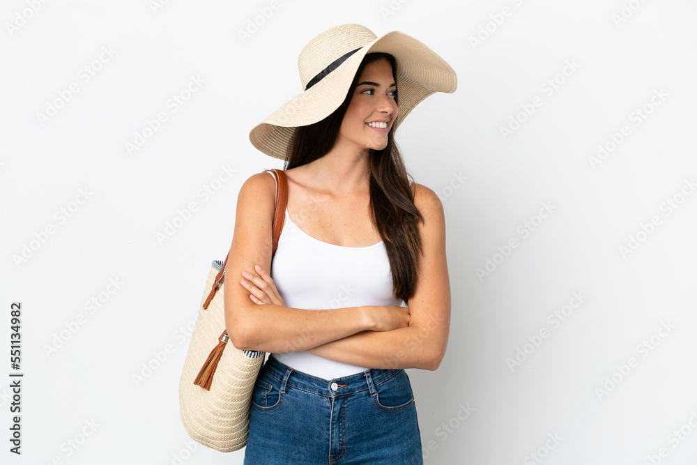 Young Brazilian woman with Pamela holding a beach bag isolated on white background looking side Young Brazilian woman with Pamela holding a beach bag isolated on white background looking side