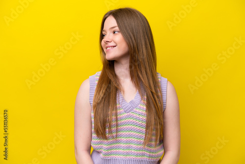Young caucasian woman isolated on yellow background looking side