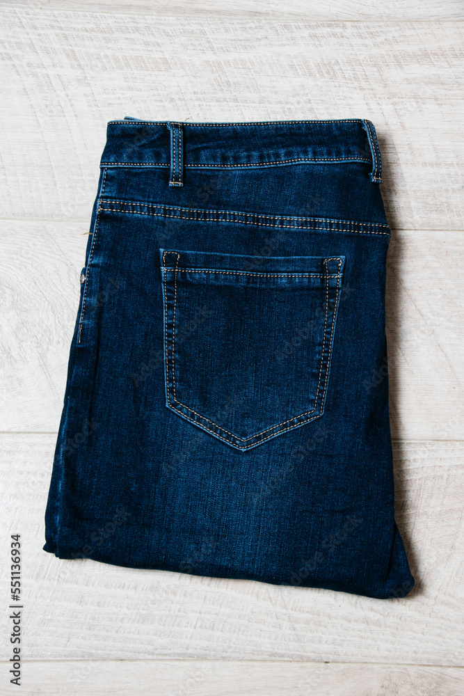 Beautiful women's jeans on a light wooden background with copy space Beautiful women's jeans on a light wooden background with copy space
