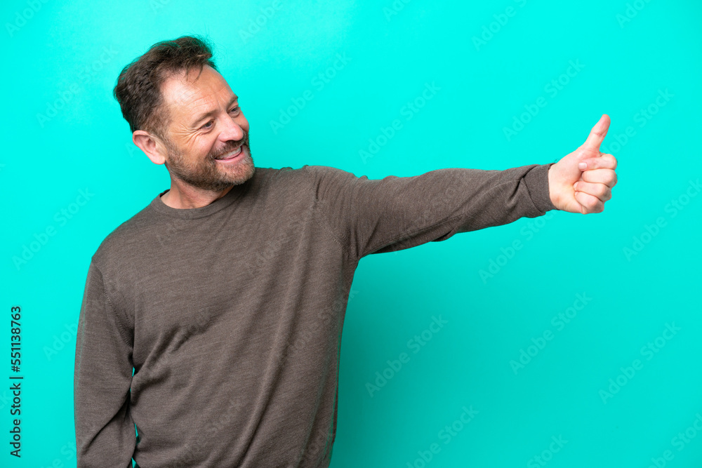Middle age caucasian man isolated on blue background giving a thumbs up gesture Middle age caucasian man isolated on blue background giving a thumbs up gesture