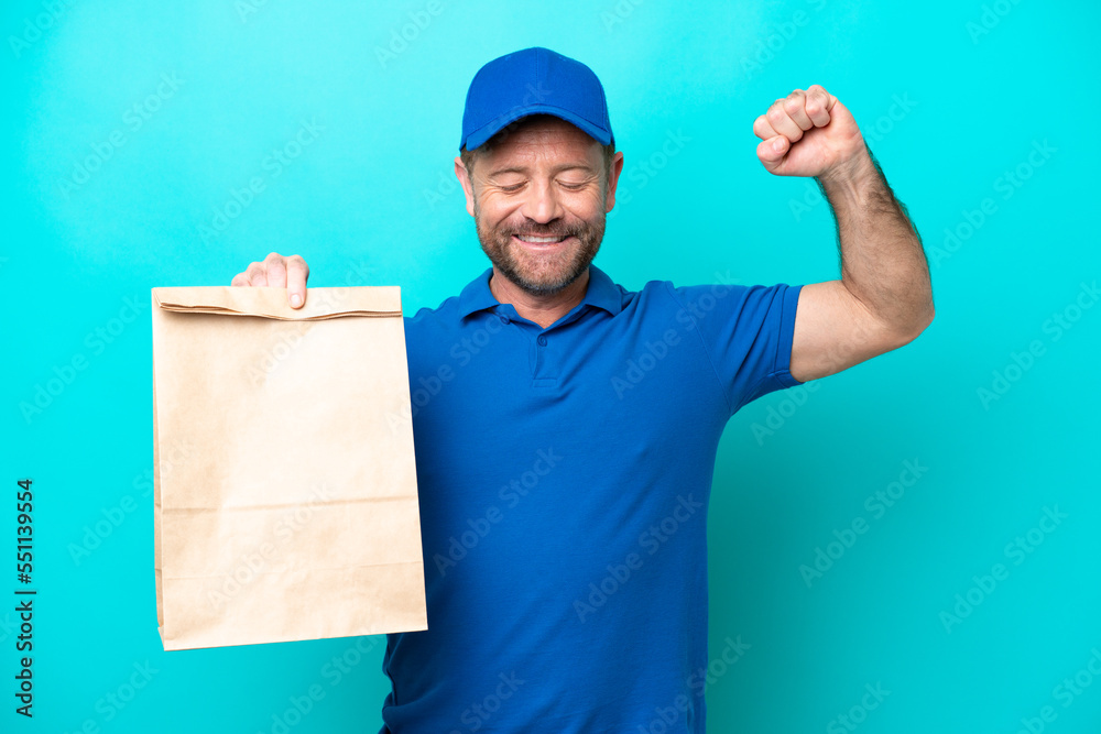 Middle age man taking a bag of takeaway food isolated on blue background doing strong gesture