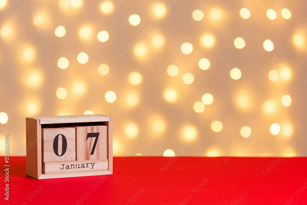 christmas, wooden calendar january 7 on red background and lights background