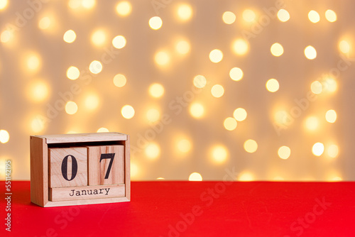 christmas, wooden calendar january 7 on red background and lights background