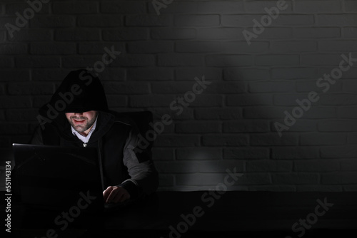 Hacker in black mask and hood at the table