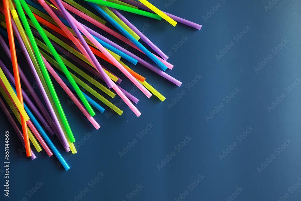 Fototapeta premium Colorful plastic drinking straws, close up as background. colored tubules for juice and cocktails on black wooden table