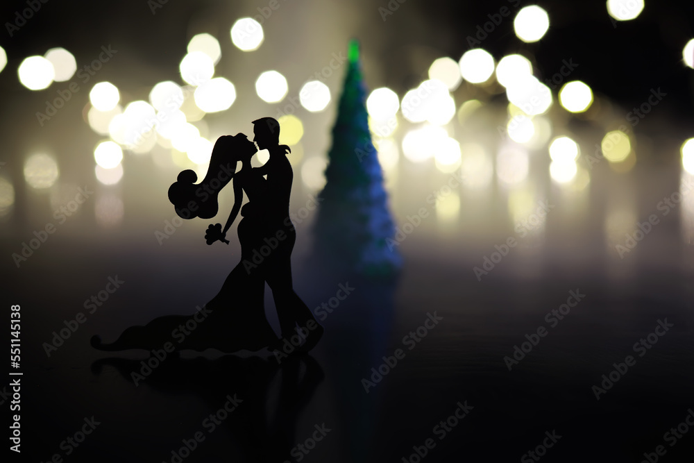 Black silhouettes of pair dancers performing. Man and woman are dancing on gray background with white backlight. Choreography. New Year's ball