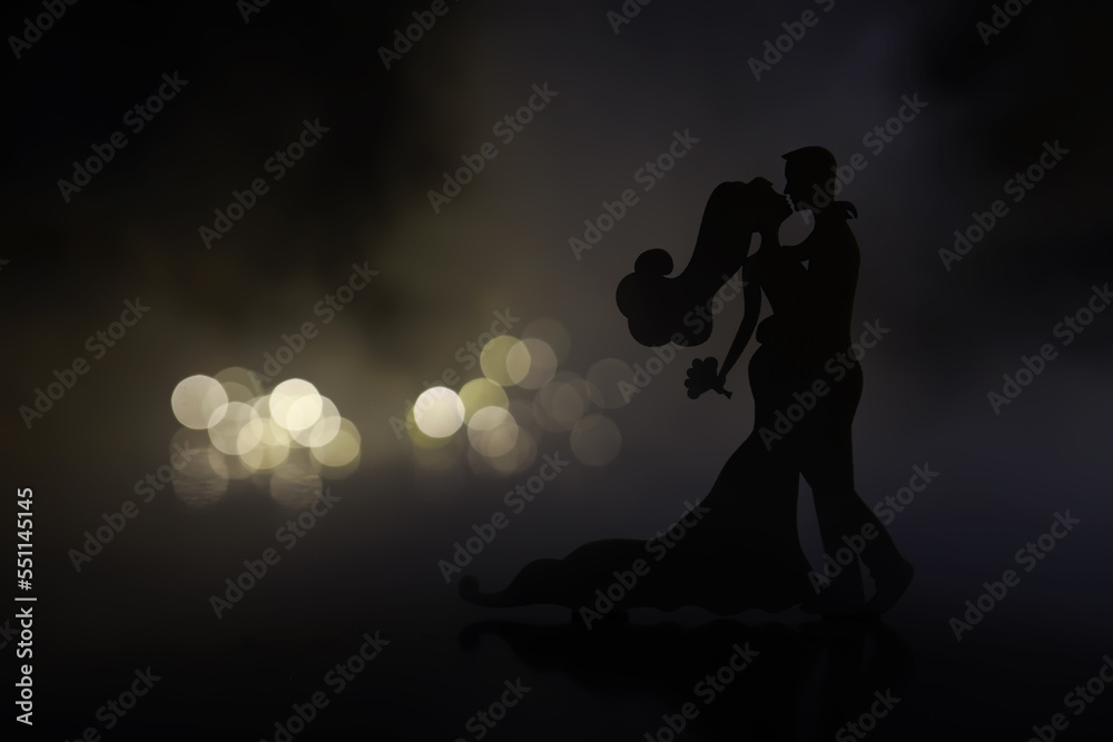 Black silhouettes of pair dancers performing. Man and woman are dancing on gray background with white backlight. Choreography. New Year's ball