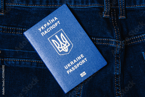 Foreign passport of a citizen of Ukraine on a dark denim background. Concept of refugees during war. photo