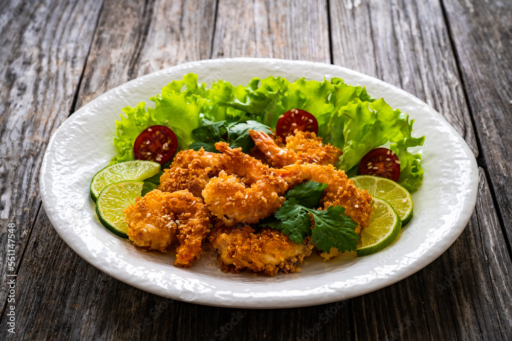 Fried panko prawns with lime, tomatoes and greens wooden table
Fried panko prawns with lime, tomatoes and greens wooden table