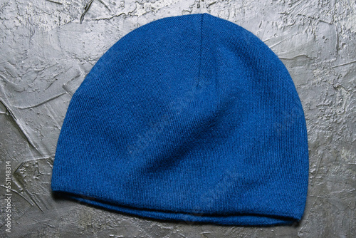 Blue knitted unisex cap on a gray background. Modern fashion concept