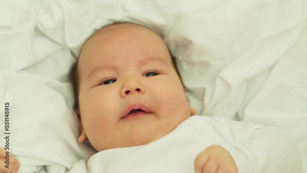 newborn baby smiles and laughs. shows emotions. baby lies on a white cloth newborn baby smiles and laughs. shows emotions. baby lies on a white cloth