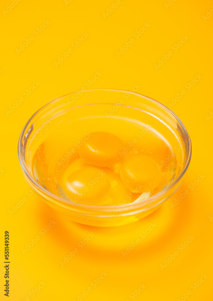 Three egg yolks in bowl plate on yellow table background. Three egg yolks in bowl plate on yellow table background.