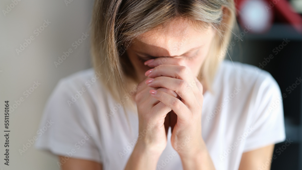 Stressed sad woman with closed eyes keeps her hands connected near her face close-up. Stressed sad woman with closed eyes keeps her hands connected near her face close-up.