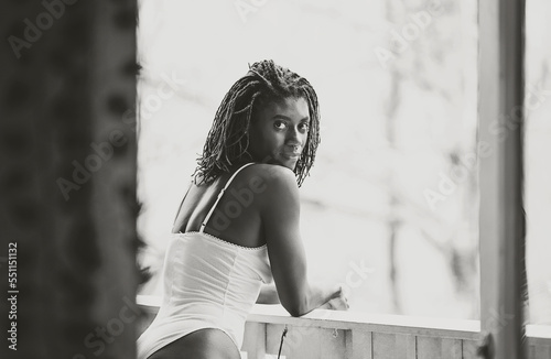 Black woman with green dreadlocks standing outside on the balcony taking in all of nature