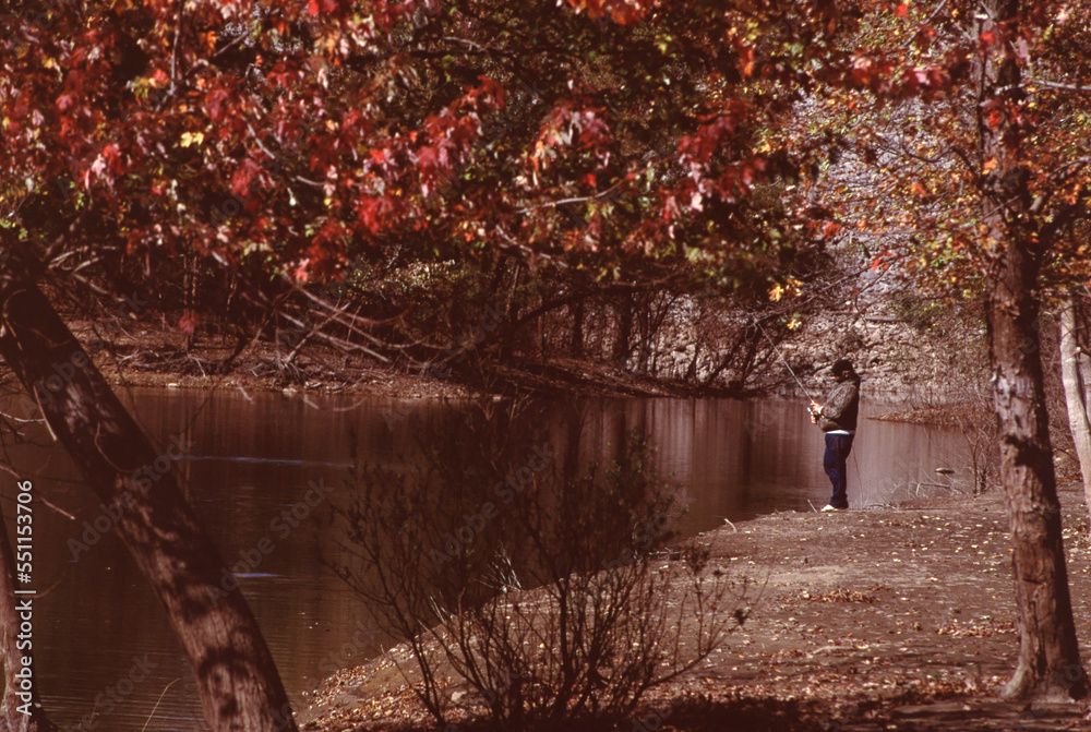 Fototapeta premium Man fishing fall color backwater along the Iowa River near the Coralville Lake, in Johnson county, IA, USA