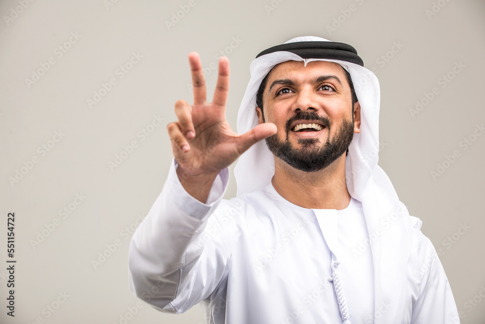 Handsome arab man wearing traditional emirate clothing portrait in studio - Middle eastern businessman isolated on cut-out gray background Handsome arab man wearing traditional emirate clothing portrait in studio - Middle eastern businessman isolated on cut-out gray background