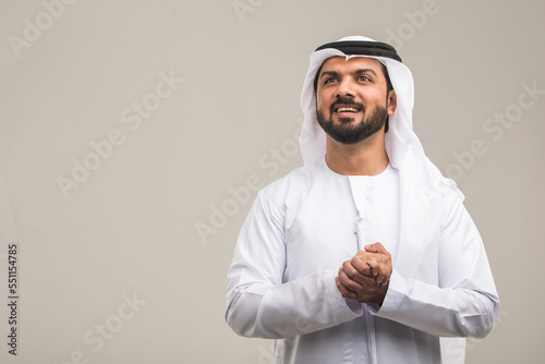 Handsome arab man wearing traditional emirate clothing portrait in studio - Middle eastern businessman isolated on cut-out gray background