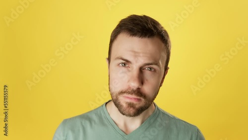Strict bearded man looking at camera over yellow background. Serious handsome man looking at camera. Close-up in 4K, UHD